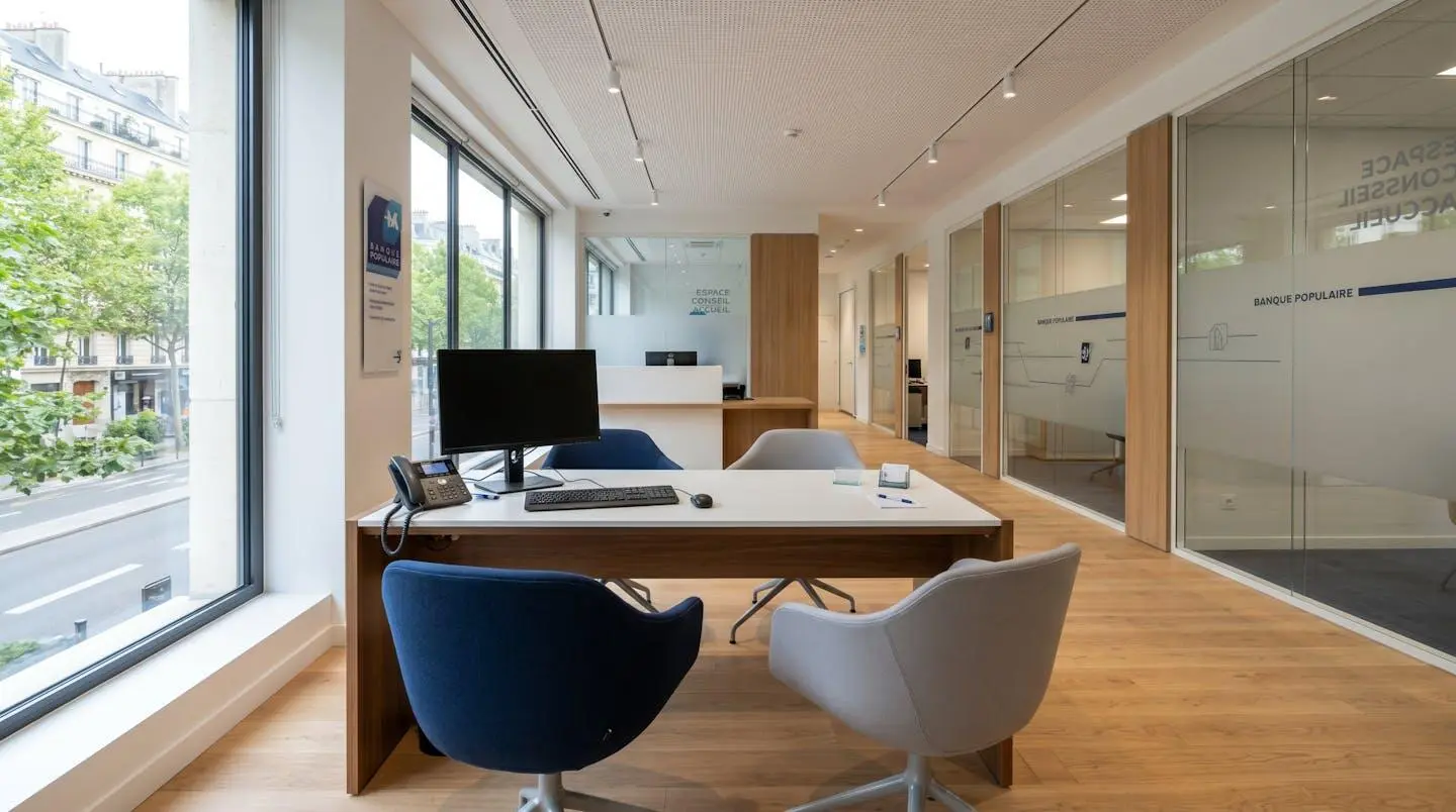 Intérieur d'une agence bancaire française moderne et vide, bureau de consultation avec deux chaises se faisant face, design contemporain épuré, lumière naturelle abondante